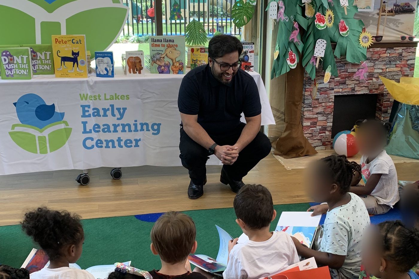 Reading event at West Lakes Early Learning Center with the logo on the table banner and standee